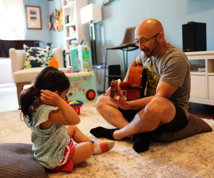 Dad and child playing guitar