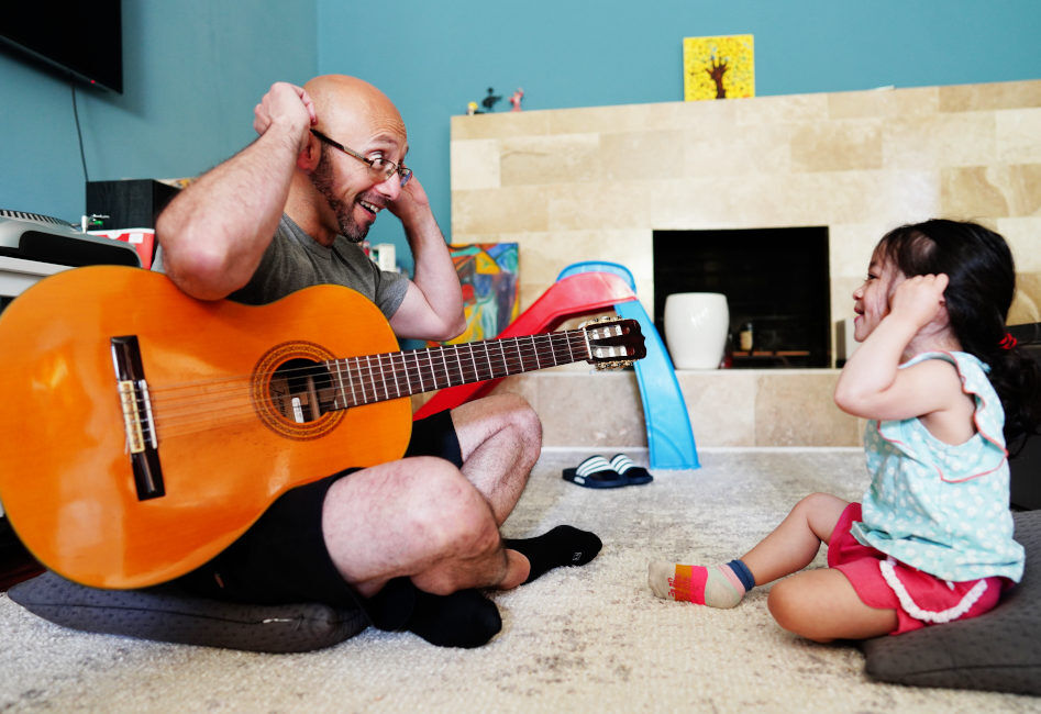 Dad and child playing guitar