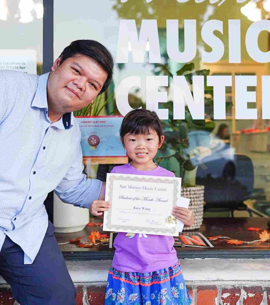 Piano student, Kara W., holding her certificate with her instructor, Armin. 