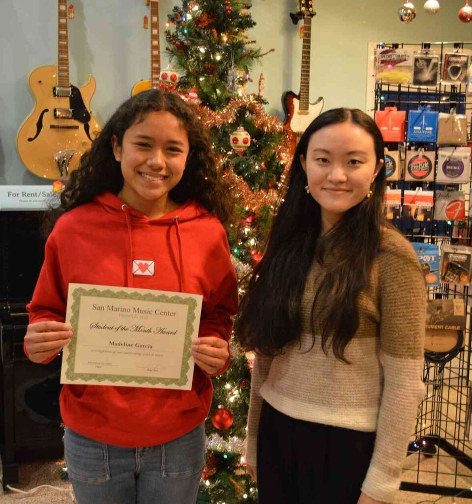 Student of the Month, Madeline G with her piano instructor, Ms. Jojo. Madeline is holding her certificate and they are smiling. 
